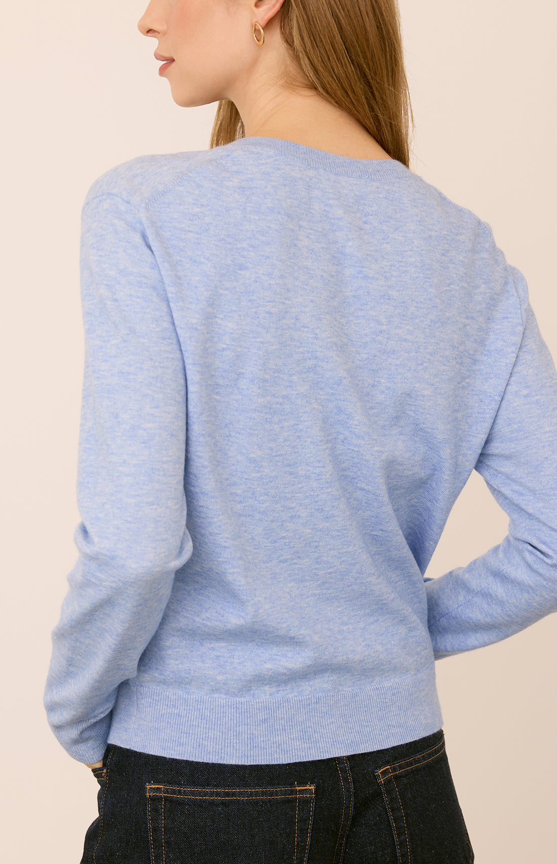 Light blue sweater worn by a woman on a beige background